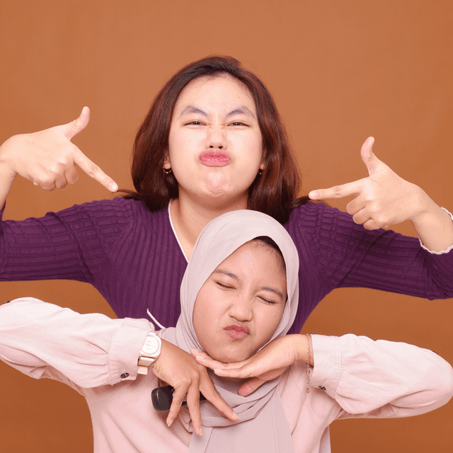 Man and woman wearing black jackets and sunglasses posing back-to-back